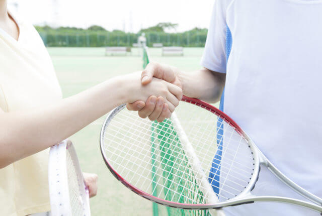 テニスコートで握手する二人
